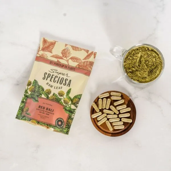 Red Bali Kratom Powder bag with bowl of kratom capsules and cup of red kratom powder.