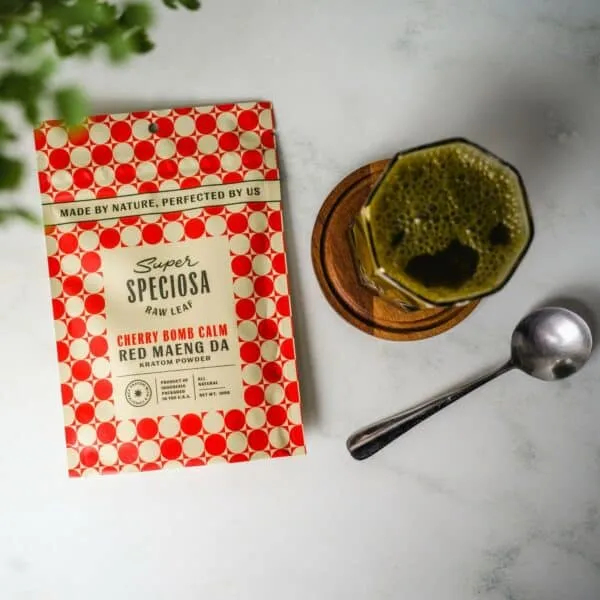 Super Speciosa's Cherry Bomb Calm Red Maeng Da Flavored Kratom Powder next to cup of kratom drink